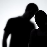 Silhouettes of upset woman and man together, experiencing life difficulties