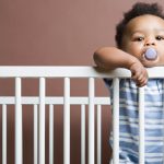 baby-boy-standing-in-cot-picture-id75403956