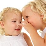 Beautiful little girl whispering to her sister