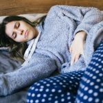 A young woman is laying on a side having stomachache