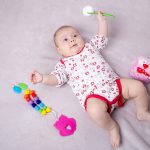 Baby girl smiling around baby toys