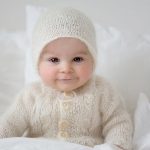 Little cute baby boy, dressed in handmade knitted white teddy bear overall, sleeping