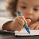 Little girl painting with colorful pencil
