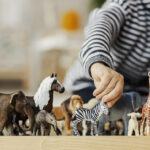 Close up of a child playing with figurines of wild animals and learning trough the game.