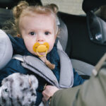 Mother straps baby into car seat