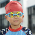 A portrait of a boy standing by the pool ready for class