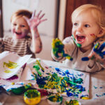 Cheerful little children having fun doing finger painting