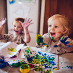 Cheerful little children having fun doing finger painting